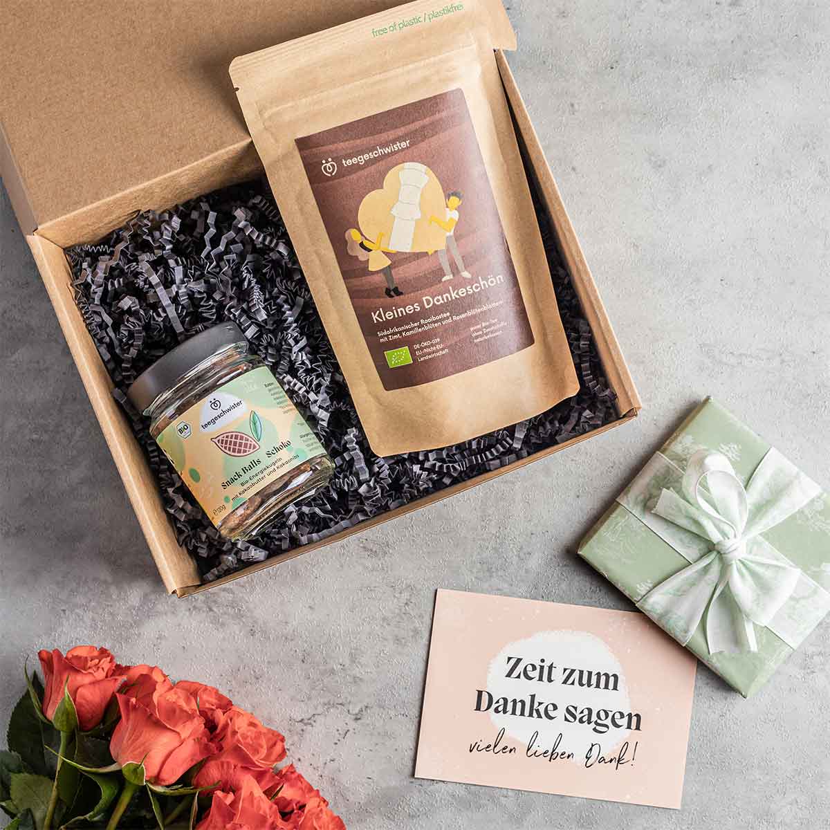 Auf diesem Bild wird die Dankeschön Geschenk-Box offen dargestellt und der kleines Dankeschön Tee mit Snack und Dankeschön Grußkarte gezeigt.