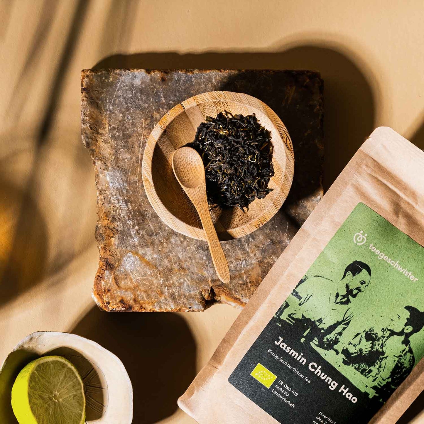 Dieses Bild zeigt die Jasmintee Verpackung und den losen Tee in einer Schale mit Löffel.