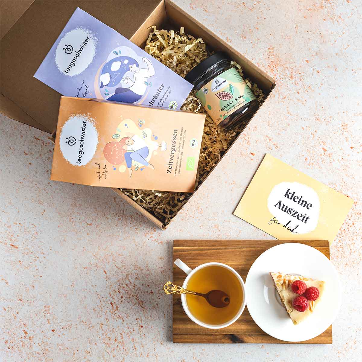 Auf diesen Bild sieht man das kleine Auszeit Geschenk-Set geöffnet neben einem aufgegossenem Tee.