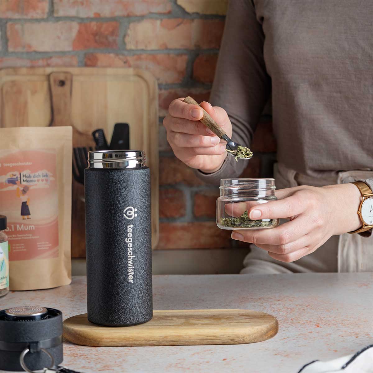 Im Bild sieht man wie loser Tee in das Sieb der Teeflasche gegeben wird.