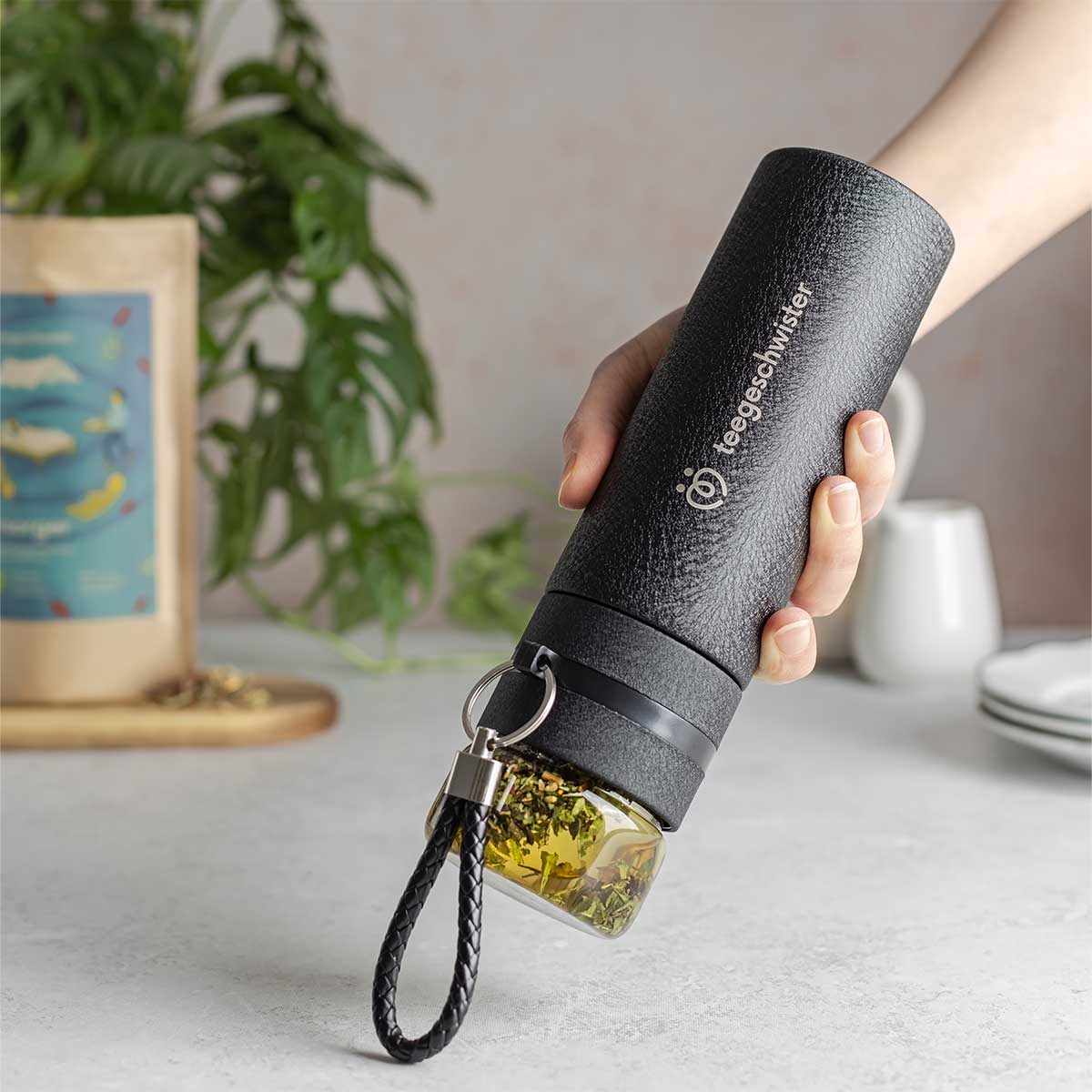 In diesem Bild wird die Teeflasche mit Sieb kopfüber gehalten um das aufgießen des Tees darzustellen.