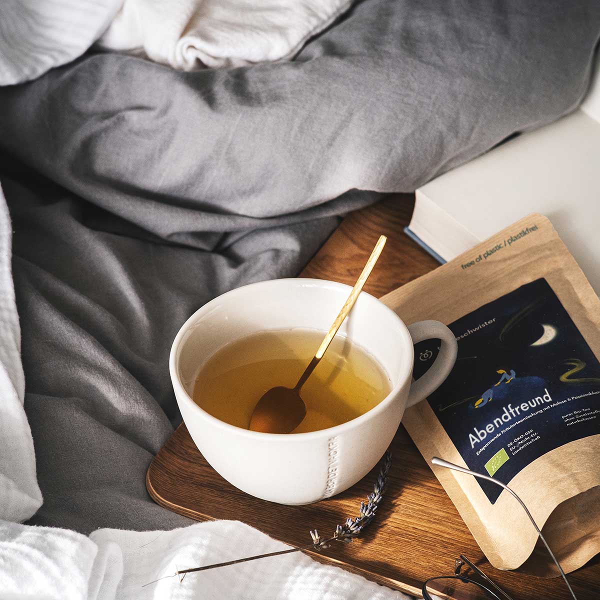 In diesem Bild sieht man den Abendtee zum einschlafen auf einem Bett mit einer Tasse aufgegossenen Tee.